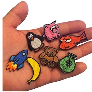 May include: A set of eight embroidered iron-on patches featuring a variety of colorful designs, including a penguin, a pig, a fish, a teddy bear, a banana, a rocket, and a money bag.
