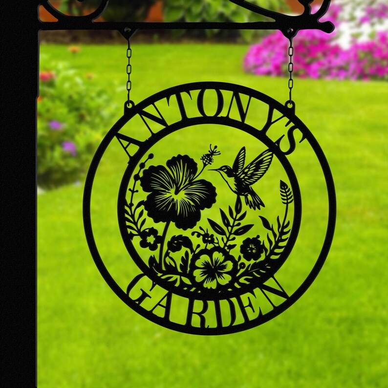 May include: Black metal garden sign with the text "Antony's Garden" in a circle. The sign features a hummingbird and floral design.