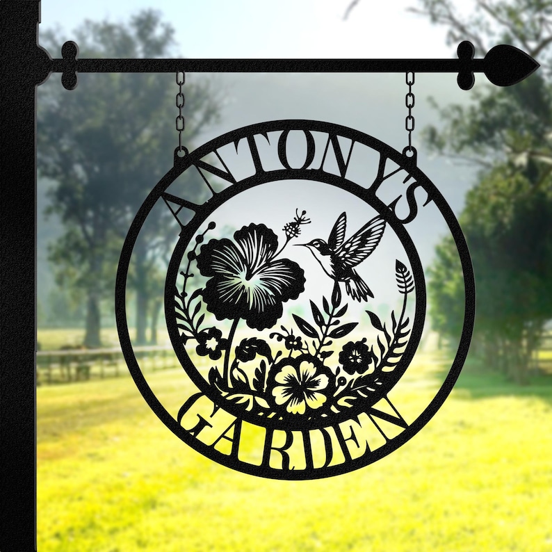 May include: Black metal garden sign with a circular design featuring a hummingbird and flowers. The sign reads "Tony's Garden".