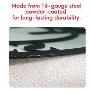 May include: Close-up of the edge of a black metal sign. The sign is made from 16-gauge steel and is powder-coated for durability.