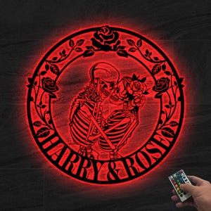 May include: A red, circular wall art piece featuring a skeleton couple embracing, surrounded by a floral wreath. The words "HARRY & ROSE" are inscribed at the bottom. A remote control is visible.