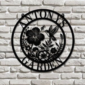 May include: Black metal garden sign with the text "ANTONY'S GARDEN" in a circle. The sign features a hummingbird and floral design.