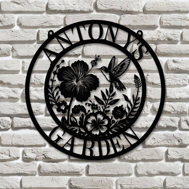 May include: Black metal garden sign with the text "ANTONY'S GARDEN" in a circle. The sign features a hummingbird and floral design.