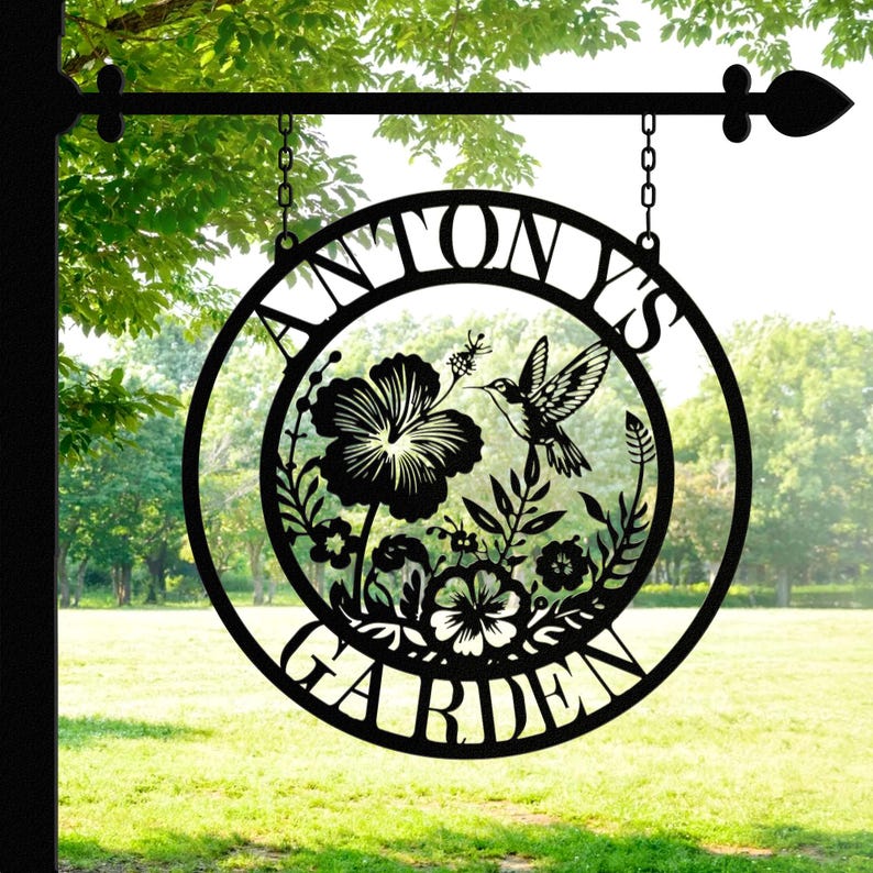 May include: Black metal garden sign with the text "Antony's Garden" in a circle with a hummingbird and flowers inside the circle.