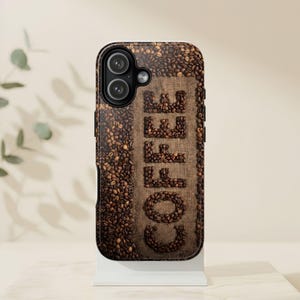May include: A smartphone case featuring a high-resolution print of roasted coffee beans scattered across the surface, with the word COFFEE spelled out in the center using arranged coffee beans against a textured brown burlap fabric background.