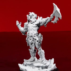 Puede incluir: Una figura miniatura pintada de blanco de una figura musculosa con cuernos que sostiene un hacha grande. La figura está de pie sobre una base rocosa.