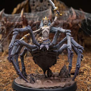 Może przedstawiać: Pomalowana miniatura figurki przedstawiająca królową pająków jadącą na pająku. Królowa nosi koronę i trzyma miecz. Pająk jest czarny i fioletowy z ośmioma nogami. Figurka stoi na okrągłej podstawie z brązową i szarą, fakturowaną powierzchnią.