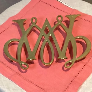May include: A gold-toned metal hot pad in the shape of the letter "W".