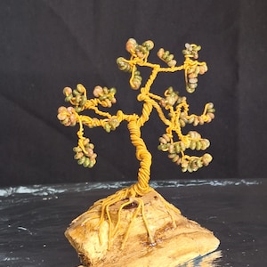 May include: A wire-wrapped tree sculpture with green and pink stones for leaves and a brown wooden base.