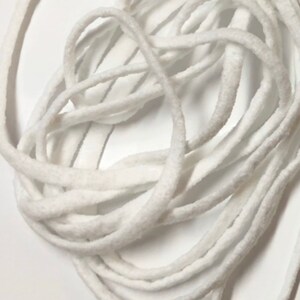 May include: A close-up of a white elastic cord, approximately 15 inches long, measured against a ruler. The cord is coiled and appears to be made of a soft, stretchy material.