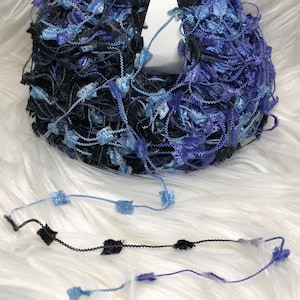 May include: A skein of blue and black yarn with a fluffy texture. The yarn is labeled "NUBS" and "Dark Horse Yarn" with a website address.