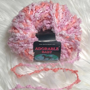 May include: A skein of pink, white, and peach yarn with a label that reads "Adorable Baby" and "www.darkhorseyarn.com".