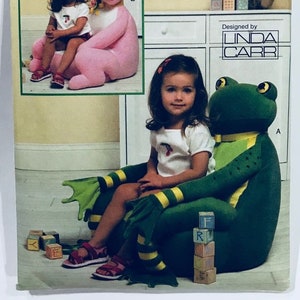 May include: A sewing pattern for a child's chair, featuring a pink bunny and a green frog. The pattern is designed by Linda Carr and is from Vogue Crafts.