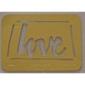May include: A yellow plastic stencil with the word "love" written in a cursive font inside a rectangular frame.