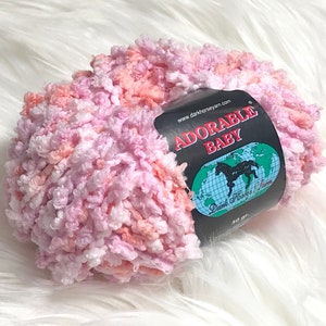May include: A skein of pink, white, and peach yarn labeled "Adorable Baby" with the website address "www.darkhorseyarn.com".