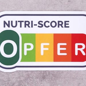 Könnte beinhalten: Ein rechteckiger Aufkleber mit abgerundeten Ecken, der oben den Text NUTRI-SCORE trägt. Darunter ist das Wort OPFER in weißen Großbuchstaben auf einem horizontalen, farbcodierten Balken zu sehen, der von Dunkelgrün zu Hellgrün, Gelb, Orange und Rot verläuft.