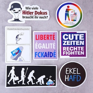 May include: A collection of seven political stickers featuring various designs and German text, including phrases like Wie viele Hitler Dokus braucht ihr noch, Halte Deine Umwelt sauber, Liberté Égalité FCKAfDÉ, Cute Zeiten Rechte fighten, and Ekel HAfD.