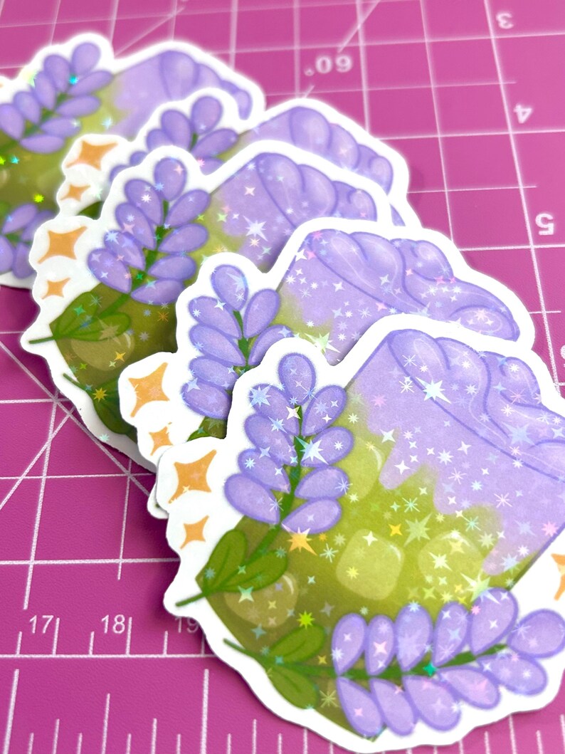 Puede incluir: Cuatro pegatinas de una bebida morada y verde con flores de lavanda y purpurina. La bebida est&aacute; en un vaso transparente con una pajita. Las pegatinas est&aacute;n en una estera de corte rosa.