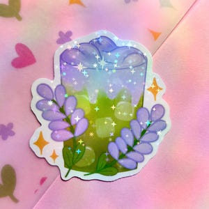 Puede incluir: Una pegatina de una bebida verde y morada con un dise&ntilde;o de flores de lavanda. La bebida tiene un remolino morado y blanco en la parte superior y est&aacute; rodeada de flores de lavanda.
