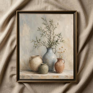 May include: A framed wall art print depicting a still life composition of four ceramic vessels in varying shades of cream, blue, and terracotta. The central blue vase holds a tall leafy green branch, while a small vase contains dried flowers.