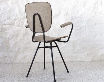 May include: A black metal chair with a beige upholstered seat and back. The chair has a single armrest on the right side and a swivel base.
