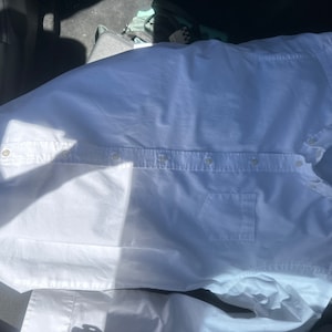 May include: A white long-sleeve button-down shirt with a pocket on the left side. The shirt has a brand label that says "CHAPS" on the right side of the collar.