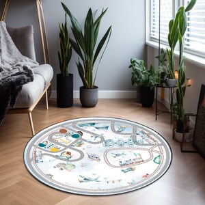 May include: A round play mat featuring a road and railway design with airplanes, trains, and hot air balloons. The mat has a white background with a gray border and is designed for children's playrooms.