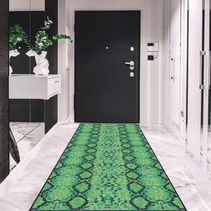 May include: A long, rectangular rug with a green and black snakeskin pattern. The rug is placed in a hallway in front of a black door. The floor is marble.