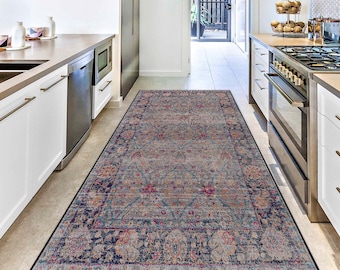 Puede incluir: Una alfombra rectangular con un diseño ornamentado de inspiración vintage. La alfombra presenta un campo central gris apagado con un patrón repetitivo de elementos florales y geométricos en tonos azules, rosas y dorados. Un borde azul oscuro enmarca la alfombra.