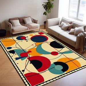 May include: A rectangular rug with an abstract design. It features large, colourful geometric shapes in red, blue, orange, and black on a cream background. The rug's border is black with a white dotted pattern. The rug is suitable for a living room.