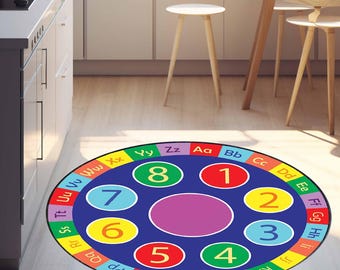 May include: A round educational rug with a blue center featuring numbers 1-8 in colorful circles. The outer ring displays the alphabet in various colors. The rug is designed for learning and play, perfect for a child's room or classroom.