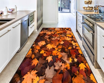 Puede incluir: Una alfombra de cocina rectangular con un diseño de hojas de otoño. La alfombra muestra una mezcla de hojas naranjas, amarillas, marrones y rojas, creando una estética cálida. La alfombra está colocada en una cocina.