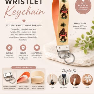 May include: A wristlet keychain featuring a beige fabric strap with a repeating graphic of Bigfoot carrying a pink flamingo pool float and pine trees. The strap has a solid orange interior, a silver-toned metal clamp, and a circular split key ring.