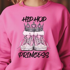 May include: Pink sweatshirt with a graphic of a crown, pink sneakers, and the text "Hip Hop Princess".