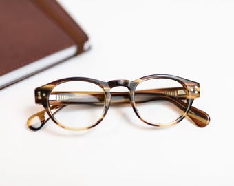 May include: Brown and tan tortoiseshell eyeglasses with round lenses.