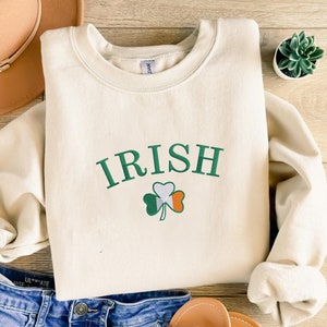 May include: A cream-coloured sweatshirt with the word "IRISH" in green letters and a green shamrock with the Irish flag colours in the centre.