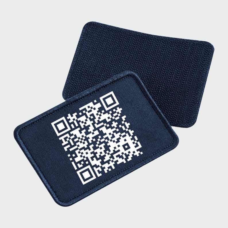 May include: A dark blue fabric patch with a white QR code printed on it. The patch has a rough texture and is designed to be sewn onto clothing or other items.