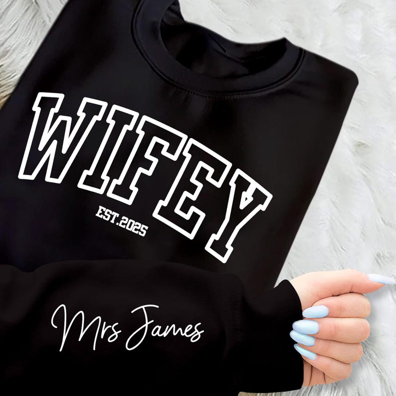 May include: Black sweatshirt with white text that reads "WIFEY EST. 2025" and "Mrs. James" on the sleeve.