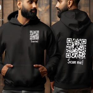 May include: Two black hoodies with a white QR code and the text "Scan me!" printed on them.