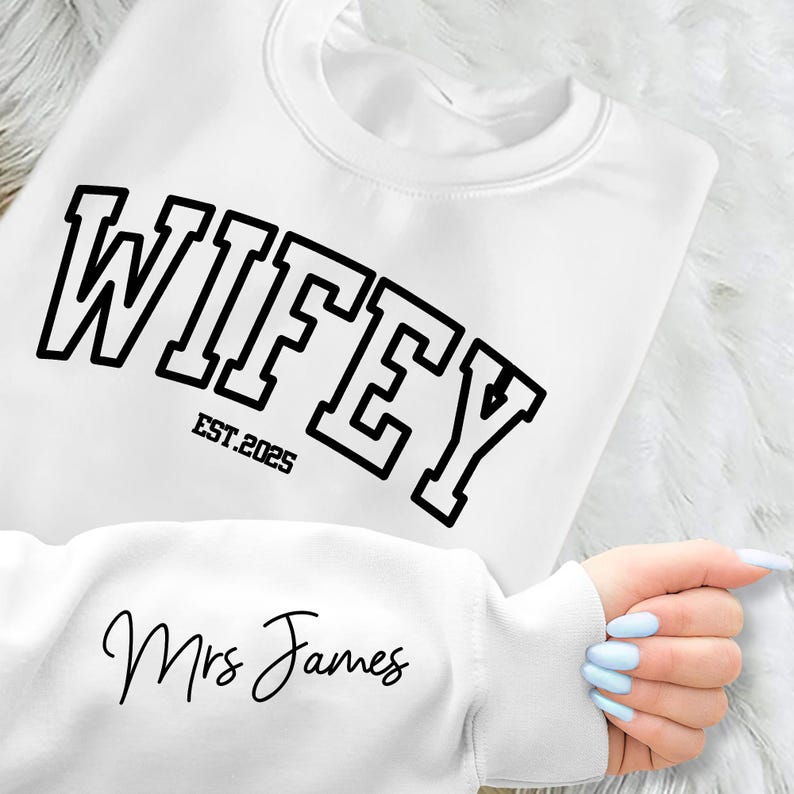 May include: White sweatshirt with black text that reads "WIFEY EST. 2025" and "Mrs. James" in cursive.