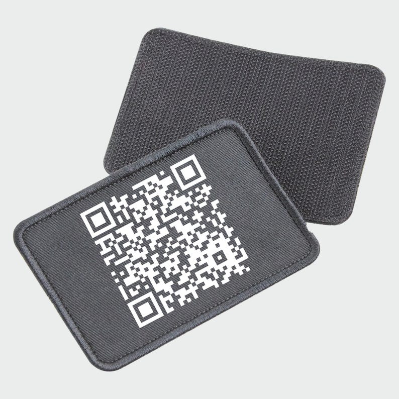 May include: A black fabric patch with a white QR code printed on it. The patch has a rough texture and is designed to be sewn onto clothing or other items.