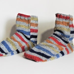 Könnte beinhalten: Ein Paar gestreifte Socken in den Farben Rot, Orange, Blau, Grau und Schwarz. Die Socken sind gestrickt und haben einen gerippten Bund.
