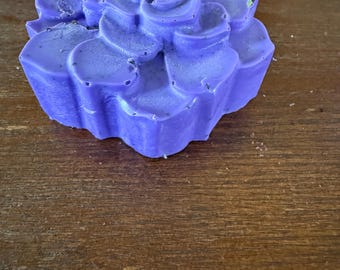 May include: A purple flower-shaped soap bar with a detailed floral design.