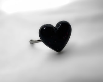 Può includere: Un pomello per armadio a forma di cuore nero con stelo color argento. Il cuore ha una finitura lucida con piccole macchie rosa. Il pomello è progettato per cassetti o armadi.