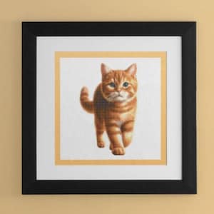 Puede incluir: Una obra de arte de punto de cruz enmarcada que presenta un gato jengibre con ojos verdes caminando hacia el espectador. El gato está representado en un estilo realista con pelaje detallado y un fondo blanco.