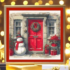 Puede incluir: Un patrón de punto de cruz enmarcado que representa una puerta roja con una corona, un muñeco de nieve y plantas en macetas. La puerta está en un edificio de piedra con dos ventanas. La imagen está sobre un fondo de luces parpadeantes.