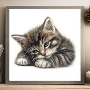 May include: A framed artwork depicting a detailed, pixelated image of a small, brown tabby kitten. The kitten is lying down on a white background. The artwork is presented in a grey frame.