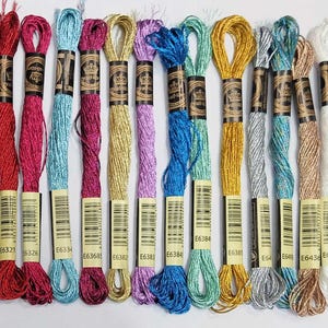 Peut inclure: Une collection de vingt-huit échevettes de fil à broder dans une variété de couleurs incluant bleu, rouge, vert, jaune, violet, noir, blanc et des tons métalliques. Chaque échevette porte une étiquette avec un code-barres.