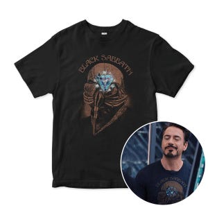 May include: Black t-shirt featuring a graphic of a person wearing a gas mask with a diamond in the eye. The text "Black Sabbath" is printed above the graphic.
