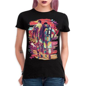 May include: Black t-shirt with a colorful graphic of two soccer players, one with the name "Ronaldo" and the number "7" on their jersey, and the other with the name "Messi" and the number "10" on their jersey.